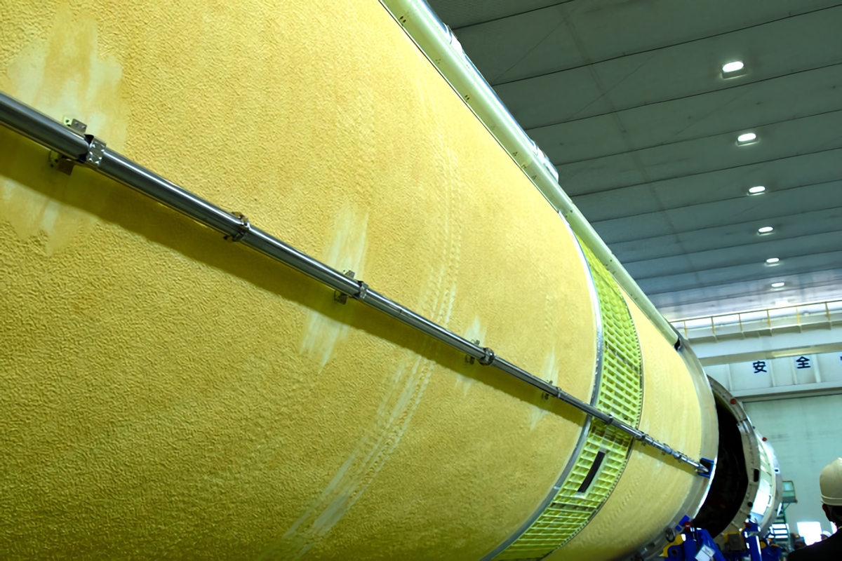 断熱材が吹き付けられたH3ロケットの表面。最初はクリーム色だが、紫外線に当たると次第にオレンジ色になってくるという=2024年3月21日、愛知県飛島村